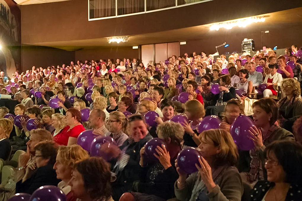 Photo d'une salle de conférence où toutes les personnes ont un ballon violet gonflé dans les mains